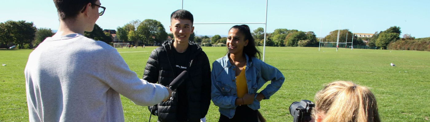 Two student being interviewed on the BHASVIC playing fields  